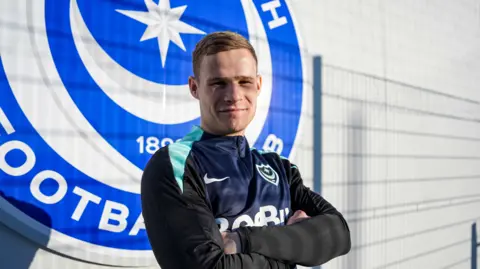 Rob Atikinson stands arms folded at Portsmouth's training ground after joining on loan from Bristol City