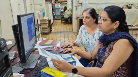 Two women, both of Parsana staff, work on their computer on the next issue of the magazine