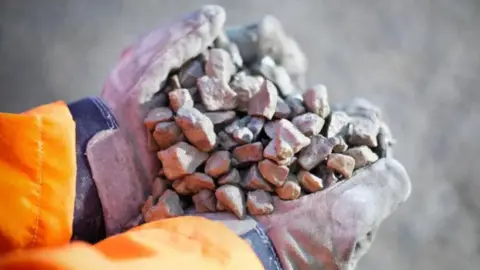 A close up image of a person's hands holding gravel