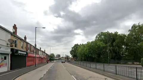 Warmsworth Road in Doncaster with shops along the left-hand side and trees along the right.