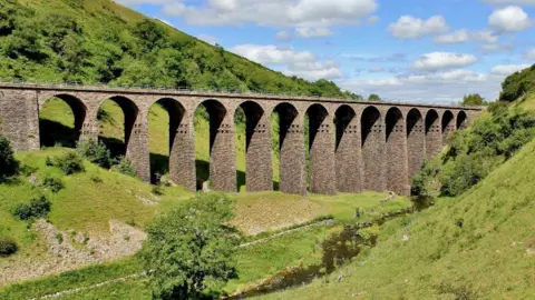 Visit Eden A general view of Smardale Gill viaduct, surrounded by grassy hills on either side.