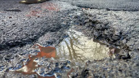 A close up image of a small pothole on a road