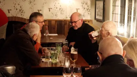 A group of men drinking pints in a pub