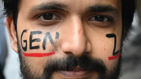 A bearded young man with the word Gen-Z painted on his face during the Cockroach Janta Party (CJP) protest at Jantar Mantar on 22 July 2026 in New Delhi, India. 