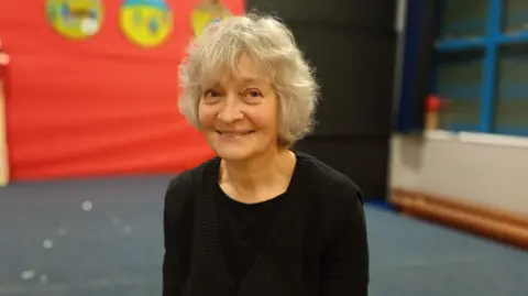 Siobhan Martin has short grey hair and is wearing a black top