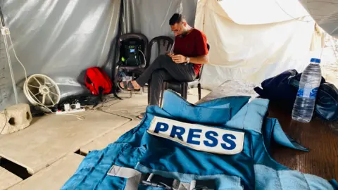 BBC is a man sitting on a chair in a tent, surrounded