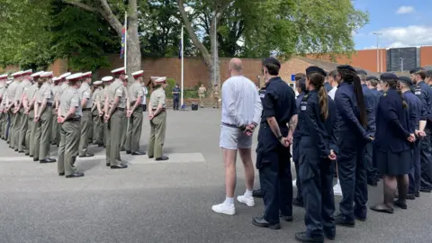 HM Naval Base Portsmouth Lines of military personnel lined up in a parade ground. A group to the left is wearing khaki green uniforms and a group to the right is wearing blue.
