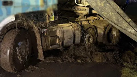 Cambs Police Wheels of a lorry can be seen caked in wed mud