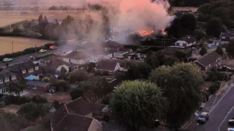 Jas Biggyp Wells Fire and police vehicles are visible as the fire continues.