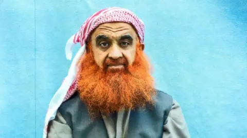 Foto milik tim hukum Khalid Sheikh Mohammed Khalid Sheikh Mohammed memiliki janggut oranye lebat dan mengenakan jilbab merah putih 