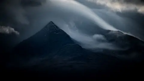 Jez Campbell Una imagen muy oscura de una montaña rodeada de nubes.