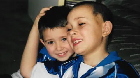 Matt and Jamie Murray pictured as children while hugging and wearing matching blue and white Colchester United tops.