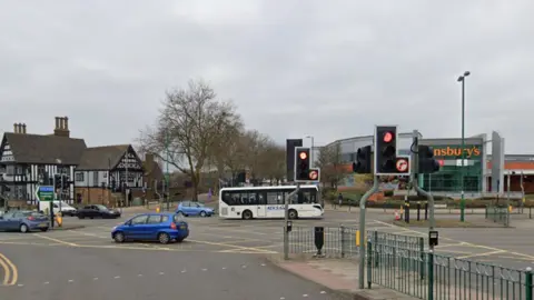 A road junction in Birmingham with traffic lights and a Sainsburys store in the background