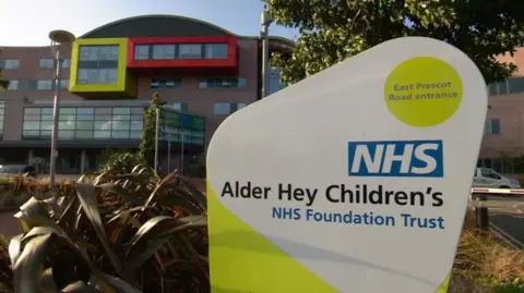 A sign says Alder Hey Children's NHS Foundation Trust. It is at the East Prescot Road entrance to the hospital.
