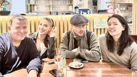 Peter Cunnah Shows a man in dark top next to a young girl in black leather jacket, next to man with tweed had, light-brown jumper and scarf and young woman with dark hair and light-brown jumper 