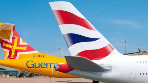 The tails of two planes, one with a yellow cross and red background and another with red and blue decals on a white background.