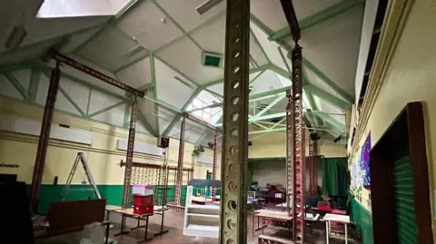 A green and cream hall with green beams. 