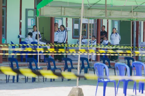 Poll workers pictured at a voting station in Shan state, Myanmar - with several empty chairs in the foreground