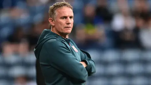 Phil Parkinson stands on the touchline with arms folded