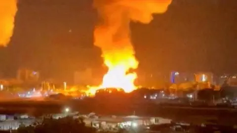 Reuters A big fireball in the distance, with smoke rising from it.