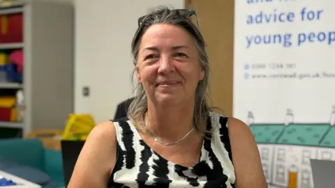 Jane Cornelius has shoulder length dark greying hair and wears a black and white top.