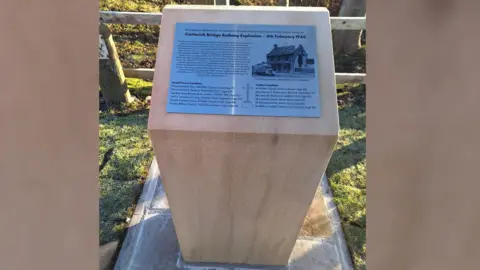 Martin Reynolds A stone plinth with a plaque on top with some written history of a munitions WW2 disaster and the names of the 12 victims who died from the explosion. 