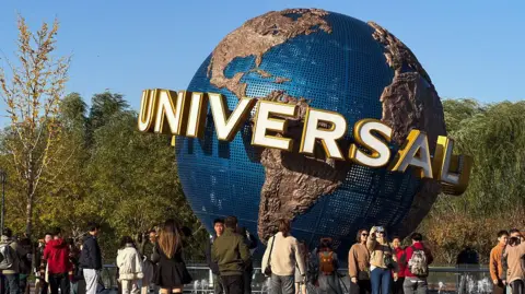 Tourists gather in front of the giant rotating globe at Universal Beijing Resort