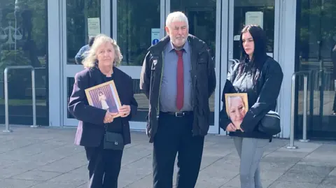 Jodey Whiting's family - with mother Joy Dove on the left - outside Teesside Coroner's Court as a second inquest into her death opens. Two of them are holding framed photos of Jodey.
