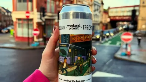 Tap and Can A can of beer is being held at the forefront of the camera. Behind it, parts of Shrewsbury town centre are visible