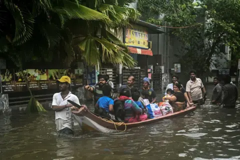 AFP via Getty Images  Volunteers steer a boat as they evacuate residents from a flooded area in Chennai on December 5, 2023, following intense rains after Cyclone Michaung made a landfall. Chest-high water surged down the streets of India's southern city Chennai on December 5, with eight people killed in intense floods as Cyclone Michaung made landfall on the southeast coast. (Photo by R__SATISH_BABU / AFP) (Photo by R__SATISH_BABU/AFP via Getty Images)