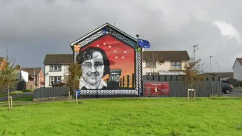 Google A grassy area where the paramilitary commemoration took place in front of a mural of the former INLA prisoner Michael Devine in the Galliagh area of Derry