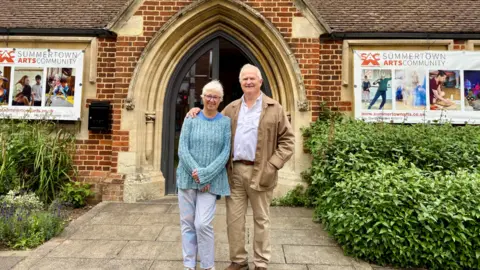 A man and a woman stood in front of a church smiling