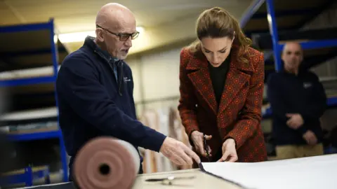 Reuters The Princess of Wales is pictured cutting a pair of jeans, guided by a member of staff