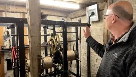 Simon Gilchrist who help renovate the clock shows off the mechanism during a public tour of the church tower.