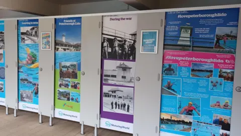 Vivacity A swimming pool's cubicle doors, each one covered with photographs taken at the lido over 90 years. Some photographs are black and white and others are colour images.