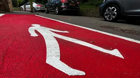 red walking path painted in country lane 