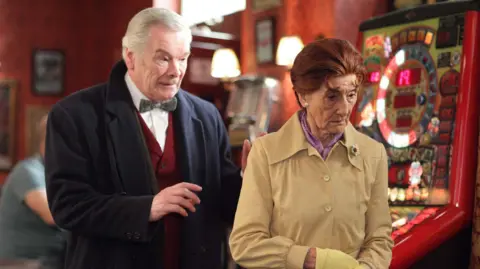 Frank Barrie, playing EastEnders character Edward Bishop, approaches June Brown as Dot Branning in the Queen Vic pub.