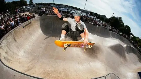 Skateboard GB/Leo Sharp Tay Cunningham competing in the park, or 'bowl', event at the British National Championships last year, which he won. He is jumping out of the bowl, grabbing his board, with crowds lining the ridge of the ramp in the background