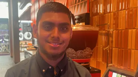 Rocky Minhaaj Uddin standing in the branch of Nando's where he works