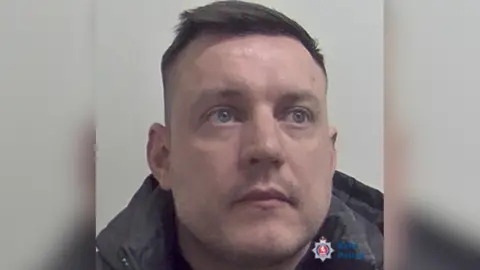 Mugshot of Jamie Stacey-Evans provided by Kent Police. Stacey-Evans looks off to the left-hand-side of the camera and has been positioned against a light grey background.