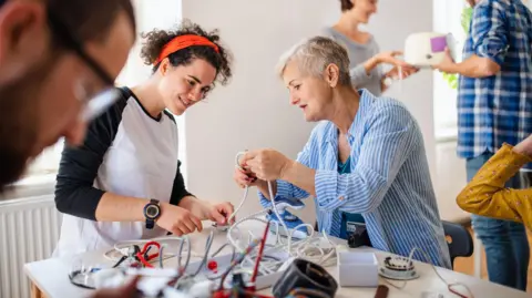 A group of people repairing household equipment in community centre at a repair café