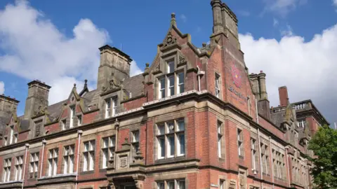 PA Media County Hall in Preston, a red-brick building with a Lancashire County Council sign on the right hand side of the building.
It's a sunny day with a few clouds in the sky.