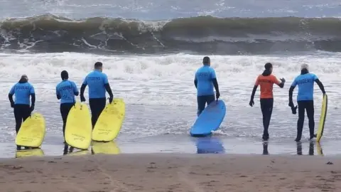 Dads Behaving Madly Six men with surfboards going into the North Sea and North Bay in Scarborough