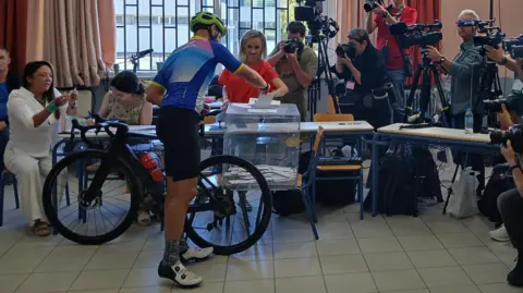 Kostas Koukoumakas/BBC Greek cyclist votes in Kifissia 