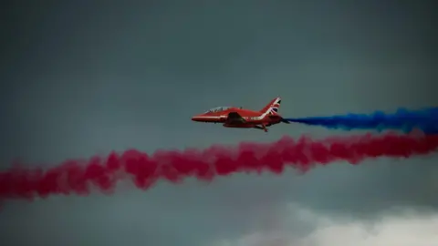 Jason Albutt A red arrow in the sky, trailing blue smoke