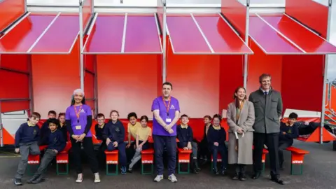 Peter Byrne School children sitting outside the mobile art museum