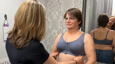 A customer in a shop having a consultation in a changing room with a bra specialist.