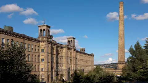 SALTS MILL The Grade II* listed ornate Yorkshire stone frontage of Salts Mill including two Italianate towers and a large disused furnace chimney.