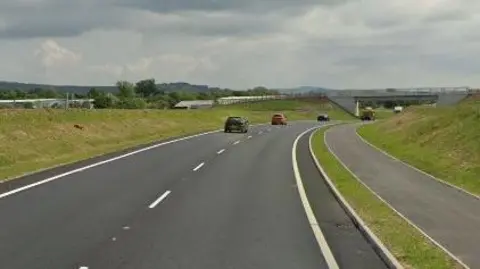 The A523, three cars drive on the left hand side of the road