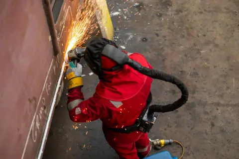 Getty Images Person in high tech protective gear using a blowtorch at the Harland & Wolff shipyard in Belfast